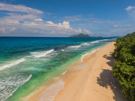 Aerial view of the turquoise sea meeting the sandy shore framed by lush greenery La Retraite Mahe Island Seychelles. Aerial view of the turquoise sea meeting the sandy shore framed by lush greenery La Retraite Mahe Island Seychelles.