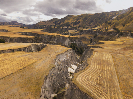 Aerial view of Toachi River Canyon featuring deep rocky gorges golden agricultural fields and rolling hills under a cloudy sky in Zumbahua Cotopaxi Ecuador. Aerial view of Toachi River Canyon featuring deep rocky gorges golden agricultural fields and rolling hills under a cloudy sky in Zumbahua Cotopaxi Ecuador.