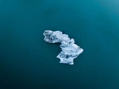 Aerial view of a solitary iceberg drifts in the serene waters of Jokulsarlon its icy form a stark contrast against the deep blue Jokulsarlon Sveitarfélagið Hornafjörður Iceland. Aerial view of a solitary iceberg drifts in the serene waters of Jokulsarlon its icy form a stark contrast against the deep blue Jokulsarlon Sveitarfélagið Hornafjörður Iceland.