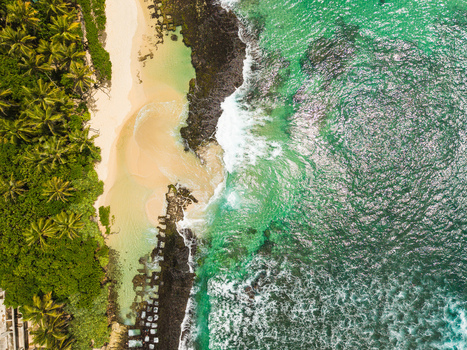 Aerial view of Thalpe Beach featuring turquoise ocean waves natural rock pools and a dense palm tree forest in Talpe Southern Province Sri Lanka. Aerial view of Thalpe Beach featuring turquoise ocean waves natural rock pools and a dense palm tree forest in Talpe Southern Province Sri Lanka.