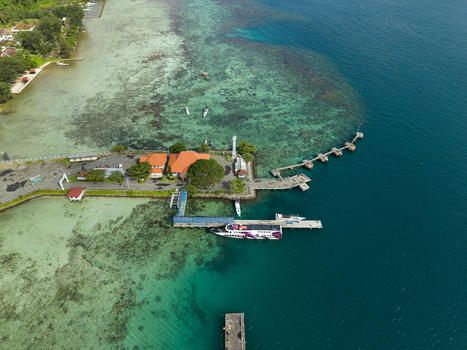 Aerial view of the ferry terminal where boats rest alongside the pier contrasting against the clear turquoise waters Karimunjawa Jawa Tengah Indonesia. Aerial view of the ferry terminal where boats rest alongside the pier contrasting against the clear turquoise waters Karimunjawa Jawa Tengah Indonesia.