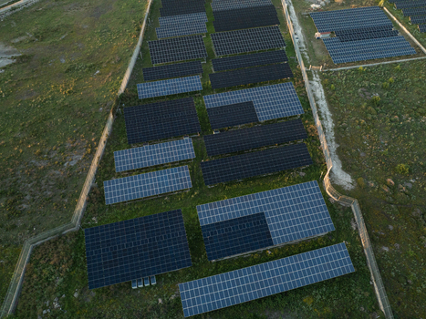 Aerial view of a large solar panel farm with rows of photovoltaic modules installed on green fields surrounded by stone walls in Augusta Sicily Italy. Aerial view of a large solar panel farm with rows of photovoltaic modules installed on green fields surrounded by stone walls in Augusta Sicily Italy.