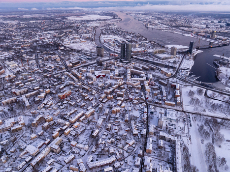 Aerial view of the city of Riga covered in snow during winter featuring the Daugava River urban rooftops and modern high rise buildings in Riga Latvia.