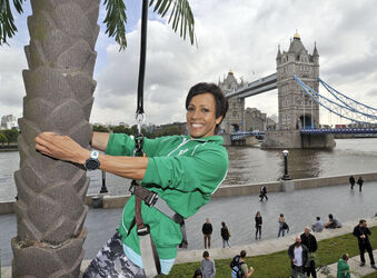 Dame Kelly Holmes climbs up a 23ft coconut tree at the Vita Coco Coconut Grove in Potters Fields London