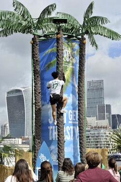Dame Kelly Holmes climbs up a 23ft coconut tree at the Vita Coco Coconut Grove in Potters Fields London