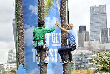 Dame Kelly Holmes climbs up a 23ft coconut tree at the Vita Coco Coconut Grove in Potters Fields London