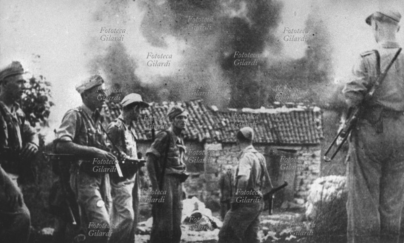 RESISTENZA rappresaglia SS: si brucia un villaggio in alta Italia, i soldati guardano un casolare in fiamme mentre un civile, probabilmente l\