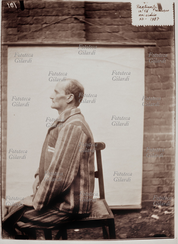 STORIA DELLA FOTOGRAFIA Ritratto segnaletico di Francesco Raglianti (omicida), eseguito con ausilio di sfondo bianco portatile; visione di profilo in divisa da carcerato. Italia, 1907.