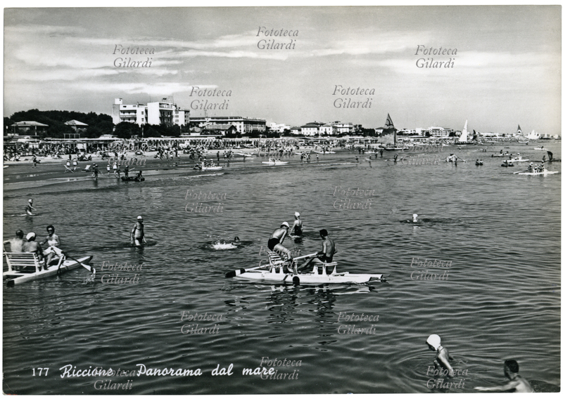 TURISMO Località balneari: "Riccione, panorama dal mare"; bagnanti e diportisti su moscone nelle acque poco profonde della riviera adriatica. Cartolina postale fotografica, Italia 1960