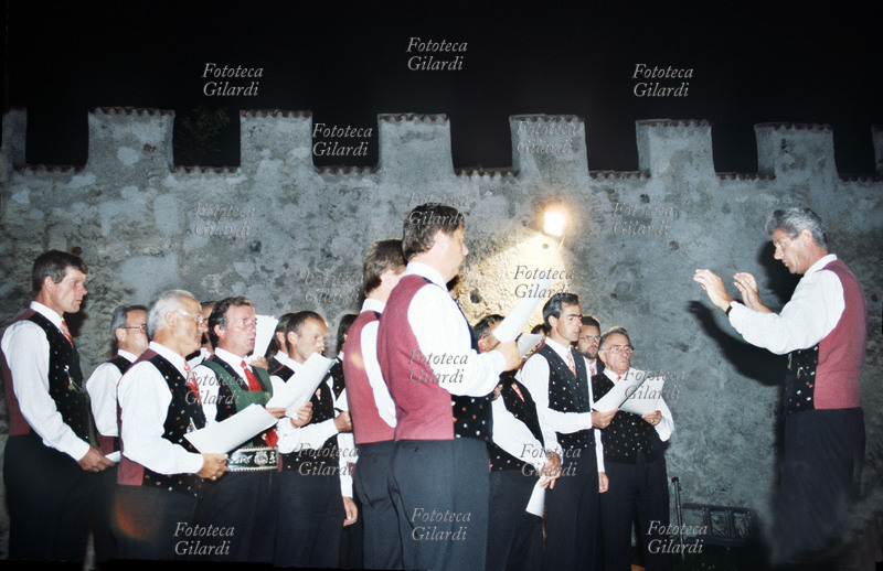 TRADIZIONI Popolari. Coro altoatesino di voci maschili si esibisce nella piazza di un castello della zona, in costume tradizionale. Fotografia Elena Piccini, Bressanone (BZ), 1992.