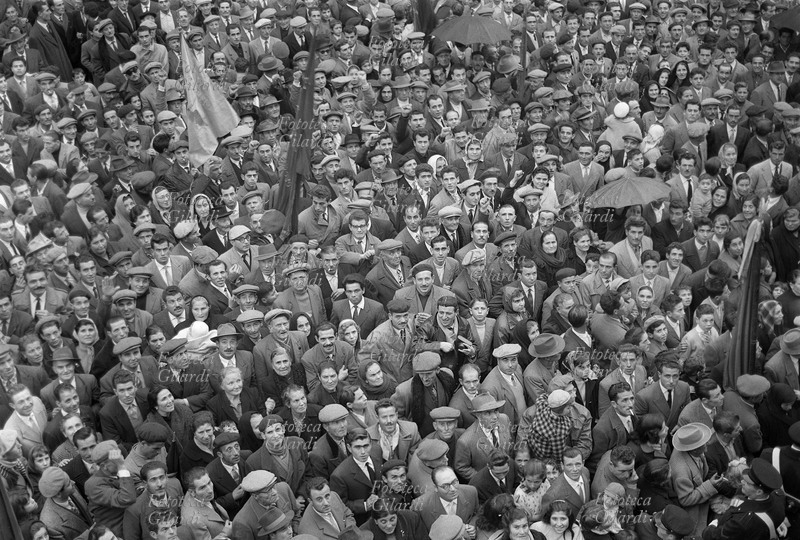 Giuseppe DI VITTORIO (1892-1957). Folla commossa a Cerignola alla manifestazione per la prima commemorazione della morte. Partecipano uomini, donne e bambini, qualcuno porta la bandiera rossa, qualcuno si ripara con l\