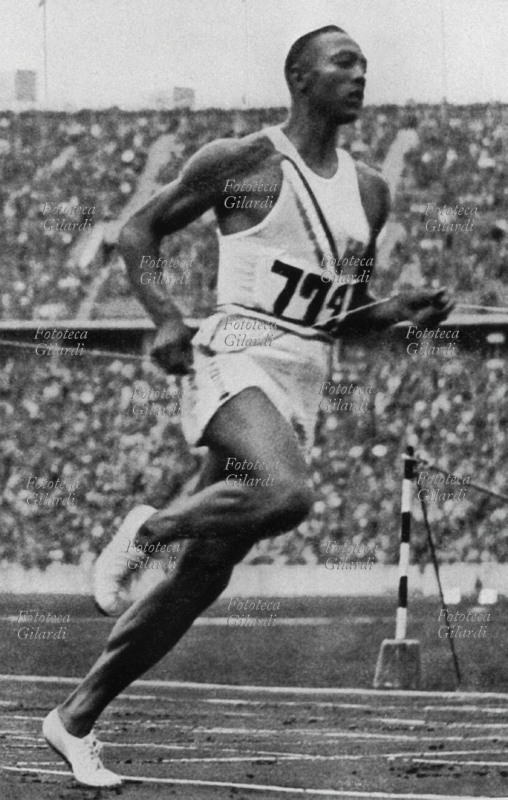 Jesse OWENS (12 settembre 1913 – 31 marzo 1980) atleta statunitense, la foto storica che lo immortala tagliare il filo dei 100 metri piani in 10"3. Nel medagliere figurano altri tre ori: per i 200 metri piani, il salto in lungo e la staffetta 4x100 metri. Germania 1936.