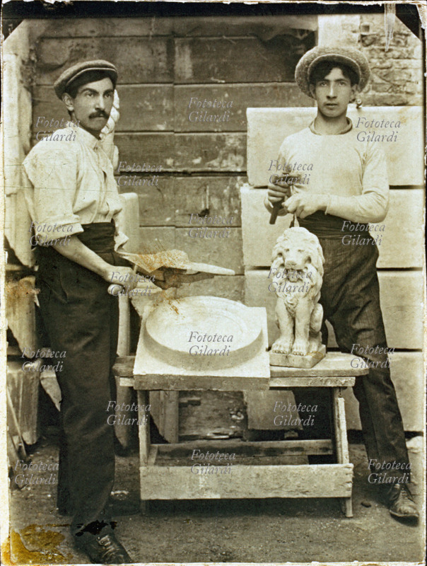 SCULTORI artigiani, produttori di statue in gesso ed in cemento usate come elementi di arredamento nei giardini o negli edifici. Uno dei due uomini sta ultimando la pulizia di un leone appena uscito dallo stampo; l\