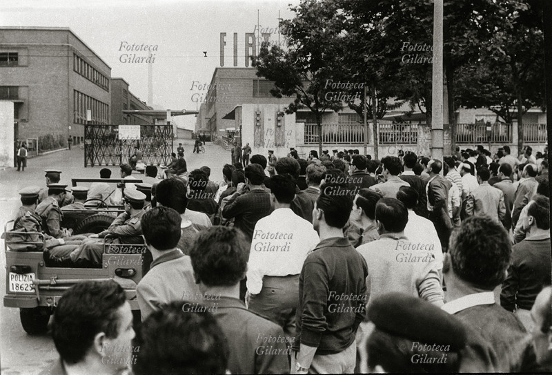 SCIOPERO Operai fermi davanti agli stabilimenti FIAT Mirafiori guardano tutti in direzione dei cancelli. Nello spiazzo è presente anche una camionetta della polizia. Italia, 1962.