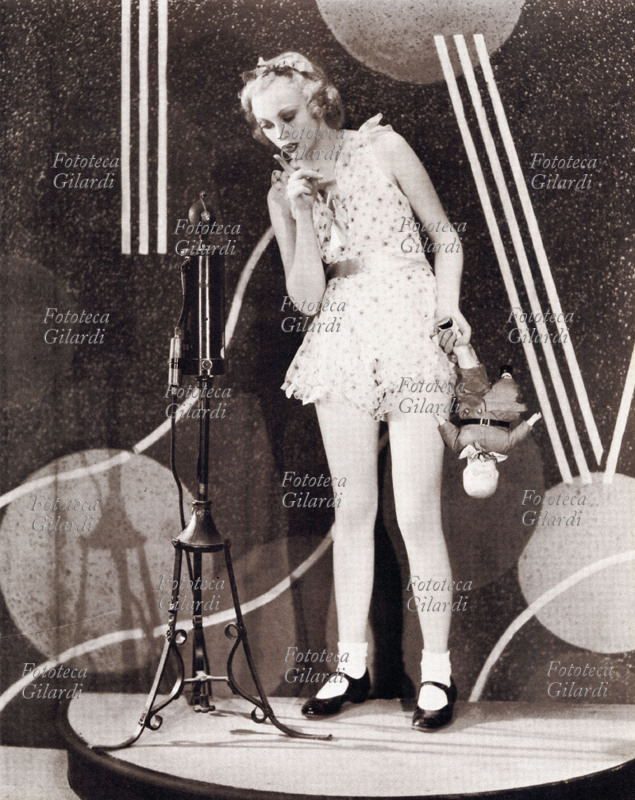 PIN UP Sheila Terry in una posa che evoca una maliziosa aria infantile. Indossa un pagliaccetto coordinato che verrà chiamato Baby Doll ispirato a questo genere di moda. 1933