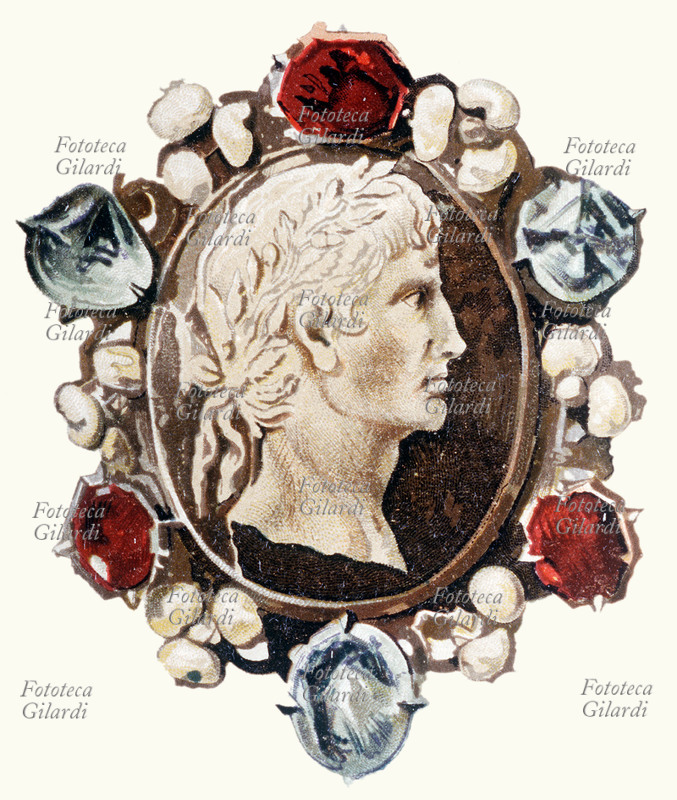 Gaio Giulio Cesare Ottaviano AUGUSTO (23 settembre 63 a.C. – 19 agosto 14) primo imperatore romano, il suo regno coincise con un periodo di pace e prosperità; riorganizzò le provincie sul piano politico, amministrativo, militare e religioso. Fondò nuove colonie e provincie annettendo e occupando nuovi territori. Abbellì Roma di nuovi grandiosi edifici: favorì la cultura e le arti, ebbe tre mogli: Clodia, Scribonia e Livia; adottò come suo successore Tiberio. Ritratto di profilo in un cammeo incorniciato di pietre dure di epoca medioevale. Cromolitografia della fine del XIX secolo.