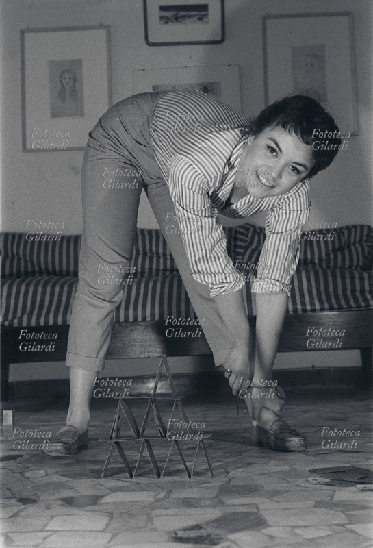 Valeria MORICONI (1931-2005) attrice italiana di cinema e teatro. Ritratta davanti ad un castello di carte, parte di un servizio fotografico realizzato da Ando Gilardi per il settimanale Vie Nuove, 1952 circa.