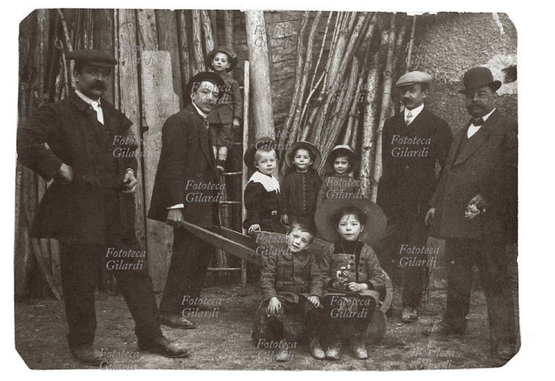 FAMIGLIA Spiritosa fotografia ricordo familiare: i bambini caricati in carriola posano insieme ai componenti maschili della famiglia vestiti per la festa, nella legnaia. Umbria, dintorni di Perugia. Italia 1915 circa