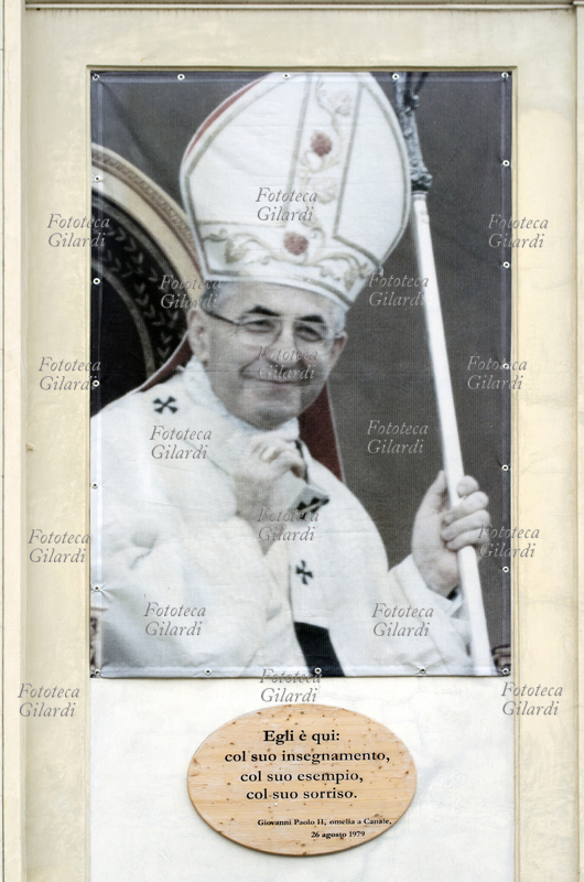 Papa GIOVANNI PAOLO I (17 ottobre 1912 – 28 settembre 1978), al secolo Albino Luciani. Ritratto e targa affissi sulla facciata della Chiesa Arcipretale della sua città natale; sulla targa una citazione da Papa Karol Wojtyla, qui giunto in pellegrinaggio per la commemorazione del primo anniversario della proclamazione a Papa del suo predecessore: "Egli è qui: col suo insegnamento, col suo esempio, col suo sorriso. Giovanni Paolo II, omelia a Canale, 26 agosto 1979". Fotografia di Elena Piccini, Canale D\