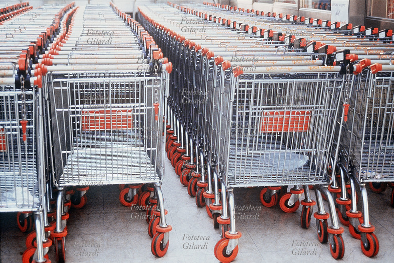 SUPERMERCATO Deposito di carrelli del supermercato Ipercoop al Centro Commerciale Bonola di Milano, a disposizione dei consumatori. Ciascun carrello è dotato di un dispositivo che lo incatena agli altri, disattivabile inserendo una moneta che non si può recuperare se non agganciando nuovamente il carrello. In questo modo i gestori si assicurano che, per non perdere la moneta, i carrelli vengono riportati in ordine al loro posto. Milano, 1990
