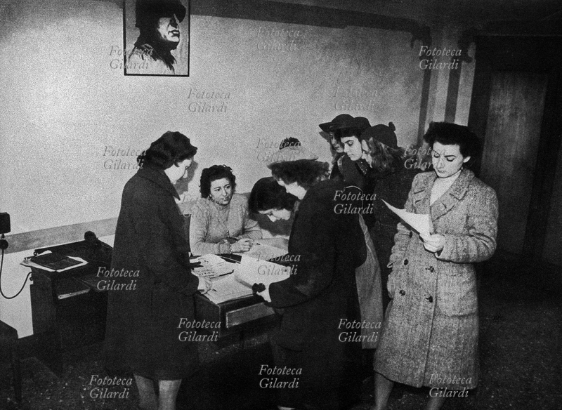 ITALIA arruolamento di ausilarie, sotto la protezione del ritratto del Duce. Milano, gennaio 1944