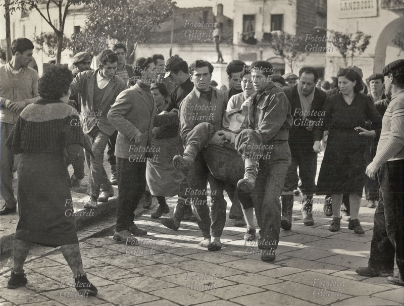LOTTE CONTADINE Rocco Girasole (1936 circa - 1956), colpito a morte dalla polizia, portato a braccia dai compagni. Lo sciopero a rovescio era stato organizzato dai braccianti di fronte al rifiuto delle autorità di iniziare i lavori per le opere pubbliche; le forze di polizia e i carabinieri hanno aperto il fuoco sui dimostranti uccidendo Rocco Girasole. Fotografia di Fortunato Lombardi, Archivio \