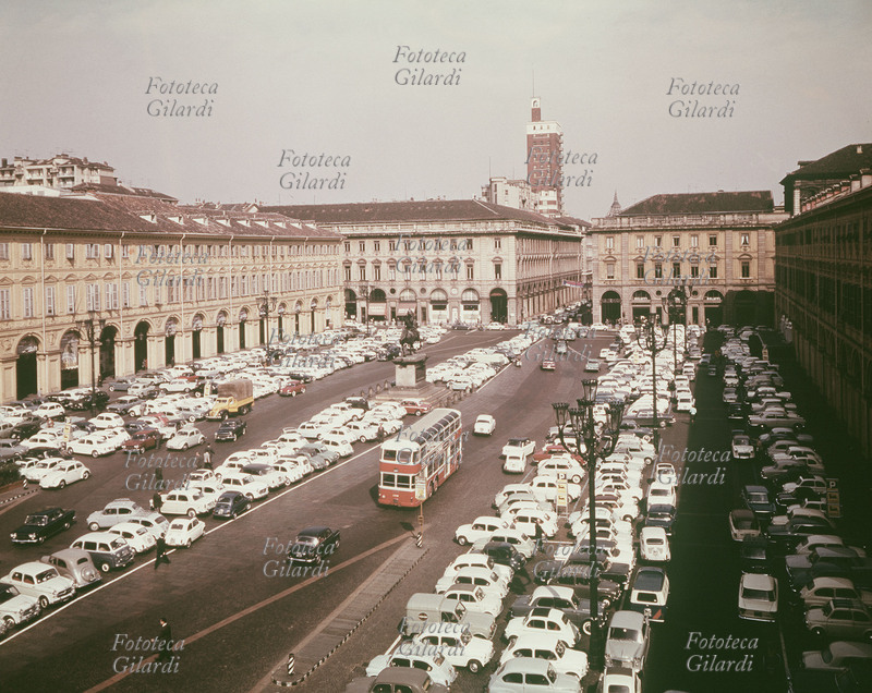 TORINO Veduta di Piazza San Carlo. La grande diffusione del mezzo automobilistico, avvenuta in conseguenza al boom economico, ha trasformato la piazza in un enorme parcheggio gremito di macchine. Nel passaggio lasciato al centro sta transitando un autobus a due piani. Fotografia, Italia 1960-69