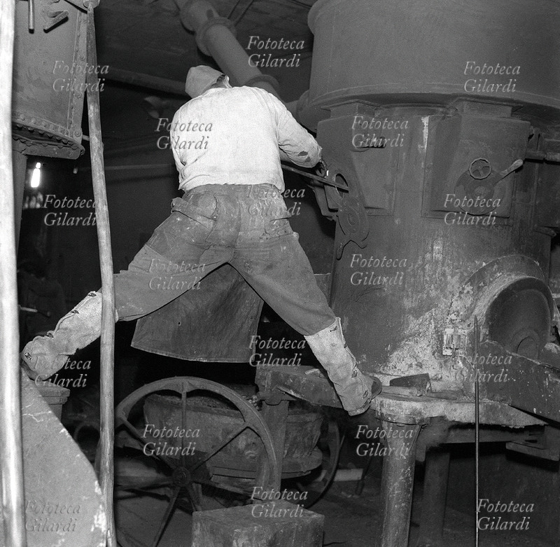 MESTIERI Operaio addetto alla manutenzione dei macchinari per la fusione nella Pignone occupata: suggestivo ritratto posteriore in officina, in bilico, arrampicato tra le macchine (vista frontale in 17324). Quando la proprietà ha deciso di licenziare tutti e serrare l\