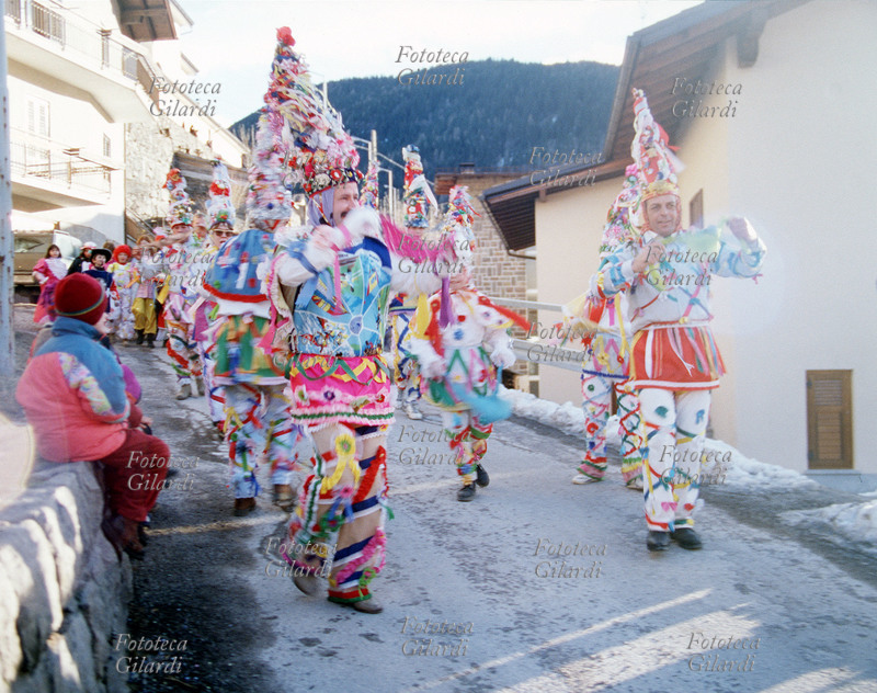 CARNEVALE di Valfloriana (Trentino). Inizio del corteo della mascherata, formato dagli Arlecchini, dai suonatori, dagli sposi e dai Paiàci. Gli Arlecchini con il tipico vestito bianco ornato di nastri multicolori e l\