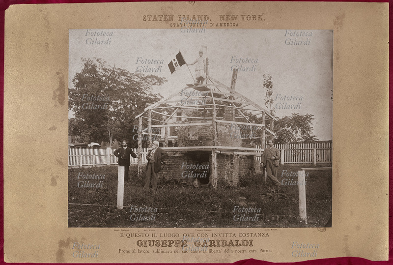 Cimelio di GARIBALDI Fotografia di uno dei cimeli di Giuseppe Garibaldi (forse il più grande di dimensioni). È il forno in cui a Caprera Garibaldi si cuoceva il pane. Questo cimelio fu acquistato da un cittadino americano (nella foto con la barba bianca) il quale lo fece ricostruire nei pressi di New York sotto una impalcatura protettiva. La figlia del collezionista posa in piedi, in cima alla costruzione con il tricolore italiano in mano. Fotografia, U.S.A. XX secolo
