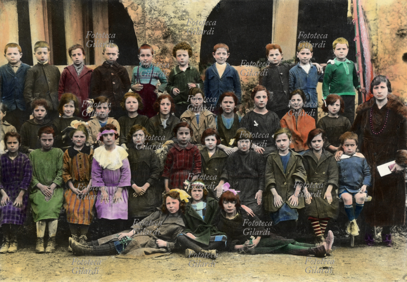 SCUOLA Scolaresca mista, anche se in prevalenza femminile, posa per una foto-ricordo. Sulla destra, la giovane maestra. Italia, inizio XX secolo