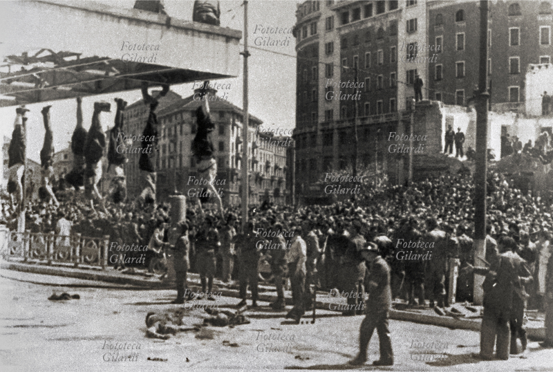 WORLD WAR II Milan: in Piazzale Loreto the population gathered as if in an open-air mortuary to observe the corpses of Claretta Petacci (28 February 1912 – 28 April 1945), Benito Mussolini (29 July 1883 – 28 April 1945) and the fascist hierarchs closest to him, captured and executed by the partisans on the way to escape, now harmless, hung by their feet to publicly and definitively represent the end of the fascist era; some climbed up to get a better look at the ruins of the bombed buildings. Milan, 29 April 1945.