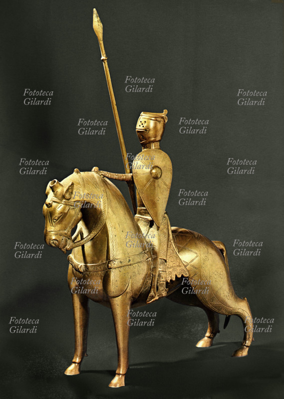 CAVALIERE crociato a cavallo con armatura e lancia in resta, in tenuta da battaglia. Statuetta da acquamanile in bronzo dorato. Francia, XIII secolo