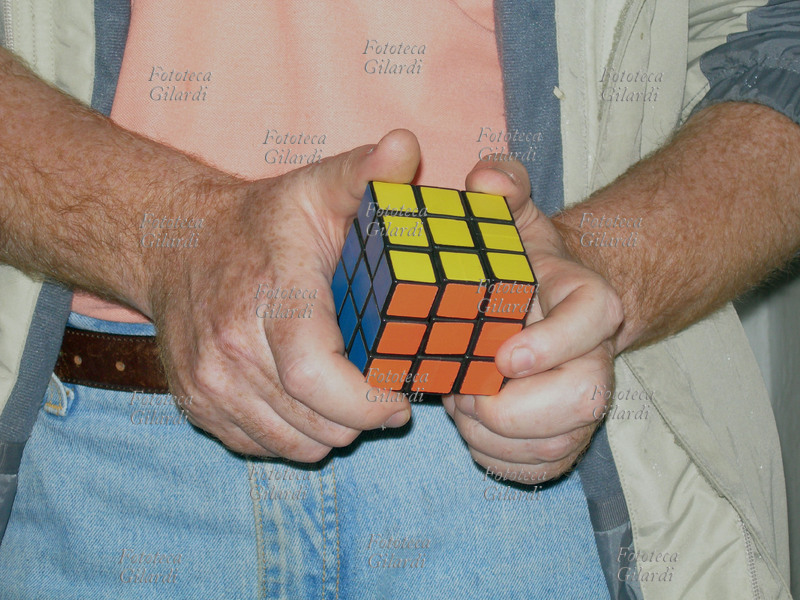 GIOCHI dettaglio delle mani con il Cubo di Rubik risolto, gioco rompicapo inventato dal professore di architettura e scultore ungherese Ernö Rubik nel 1974. Lo scopo del gioco è di risalire alla posizione originale dei 26 cubetti portando il cubo ad avere per ogni faccia un colore uguale. Il cubo può assumere ben 43.252.003.274.489.856.000 combinazioni diverse, solo una delle quali è quella corretta. Il gioco divenne molto diffuso e popolare, la stima delle vendite nel 1982 supera i 100 milioni di pezzi.
