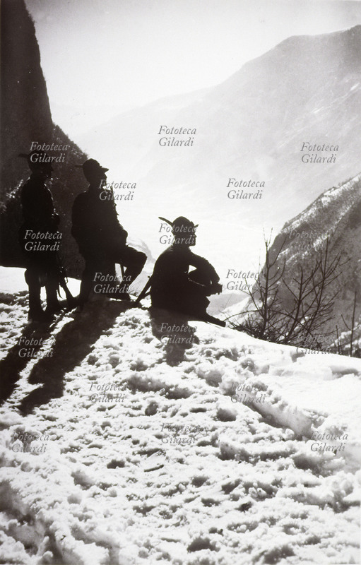 I GUERRA MONDIALE tre alpini ripresi romanticamente in un controluce al tramonto che staglia le loro silhouettes sul fondo di montagne innevate. Italia 1915 - 1918
