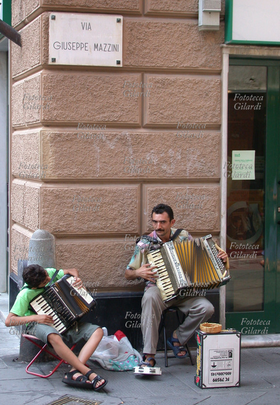 MUSICA Coppia di suonatori ambulanti di fisarmonica, ragazzo e adulto; i due sono seduti all\