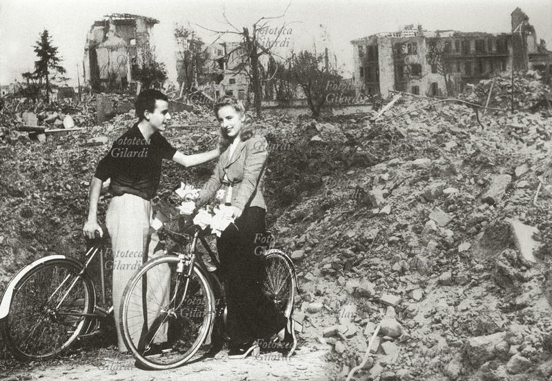 II GUERRA MONDIALE Due fidanzati in bicicletta ritratti sullo sfondo della città di Firenze dopo il dopo il bombardamento del 2 marzo 1944. Fotomontaggio, 2004.