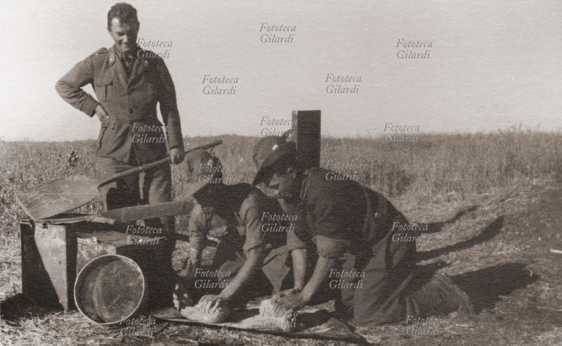 II GUERRA MONDIALE gruppo di alpini in un momento di ristoro, prepara il pane che cuoceranno in un forno costruito con un vecchio bidone di benzina (vedi #16809). Durante la spedizione in Russia l\