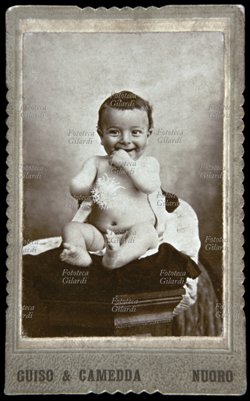 CHILDREN about one year old boy laughing and playing with a sponge; naked portrait sitting on a chair. It is probable that behind him there was a wet nurse (or the mother) who held him, then skillfully retouched by the photographer. There are some revealing details. (carte de visite senza nome see # 33270) Photography Guiso & Camedda, Italy, Nuoro around 1895