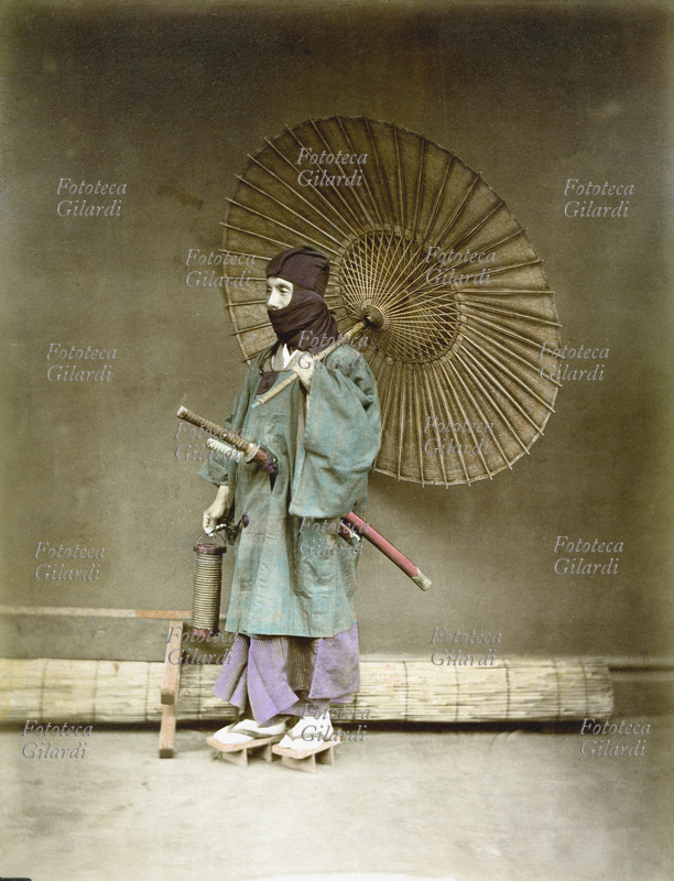GIAPPONE 1890 Ritratto di guardia armata di spada ed incappucciata con grande ombrello. Il termine con cui si chiama oggi questa figura militare del Giappone feudale (dal 1185 al 1868 circa) è ninja. Il ninja è l\