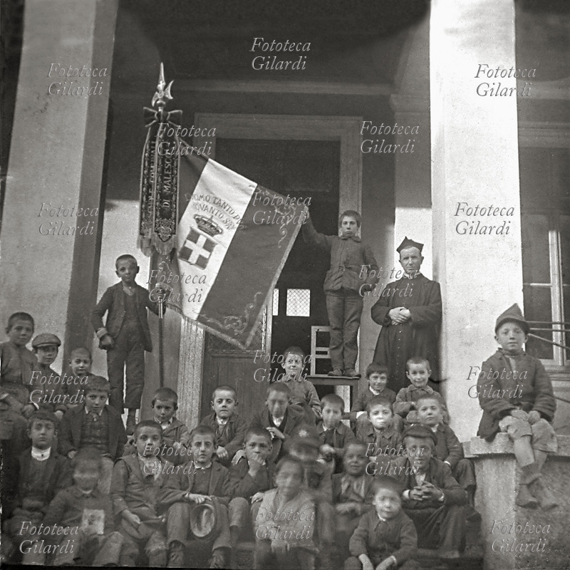 Malesco SCHOOL, the flag of the school. Photography memory on the steps dell income: the group of the students with taught (a priest). Photo of Giovanni Bertina (1849 - 1937)