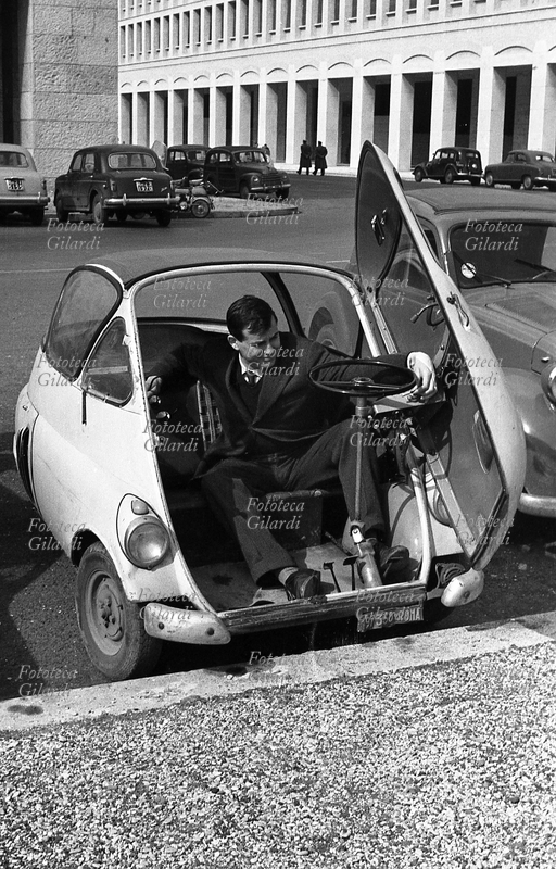 IV CONGRESSO della CGIL riunito a Roma EUR. Un partecipante arriva a bordo della sua Iso Isetta, una microvettura ad apertura con portellone frontale prodotta dalla casa automobilistica italiana Iso di Bresso (Milano) tra il 1953 ed il 1956 e, su licenza, dalla tedesca BMW tra il 1955 ed il 1962. La BMW Isetta, nel 1955, è stata la prima automobile al mondo prodotta in serie a basso consumo di carburante. Fotografia di Ando Gilardi (1921 - 2012), #andogilardi, Roma, 27 febbraio/4 marzo 1956.