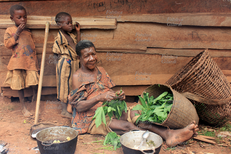 AFRICA anziana donna prepara foglie da cuocere. Il villaggio appartiene a un gruppo etnico chiamato genericamente \