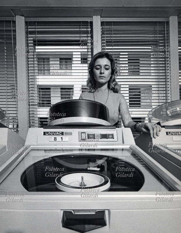 SETTORE TERZIARIO Impiegata della Banca Alto Milanese di Busto Arsizio al lavoro su calcolatori elettronici UNIVAC. Le memorie su grossi dischi magnetici occupano intere stanze. Busto Arsizio, fotografia di Ando Gilardi, 1970 circa