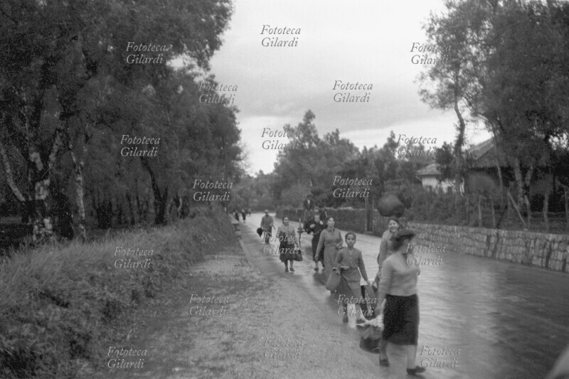 AGRICOLTURA raccoglitrici di olive calabresi, nel territorio del comune di Gioia Tauro (RC), tornano ai loro alloggi, sotto la pioggia, dopo una dura giornata di lavoro. Fotografia di Ando Gilardi (1921 - 2012) #andogilardi, Italia 1957.