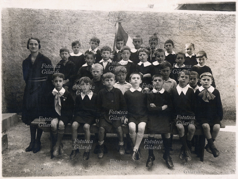 SCUOLA gruppo scolastico di classe elementare maschile: a fianco la maestra, un ragazzino dell\