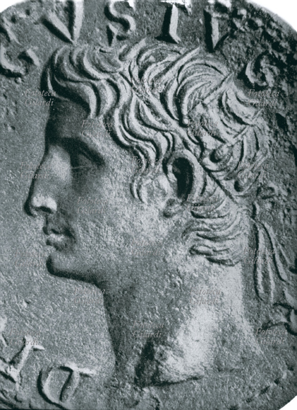 Gaio Giulio Cesare Ottaviano AUGUSTO (23 settembre 63 a.C. – 19 agosto 14) primo imperatore romano, il suo regno coincise con un periodo di pace e prosperità; riorganizzò le provincie sul piano politico, amministrativo, militare e religioso. Fondò nuove colonie e provincie annettendo e occupando nuovi territori. Abbellì Roma di nuovi grandiosi edifici: favorì la cultura e le arti, ebbe tre mogli: Clodia, Scribonia e Livia; adottò come suo successore Tiberio. Ritratto di profilo da antica moneta. Italia, I secolo circa.