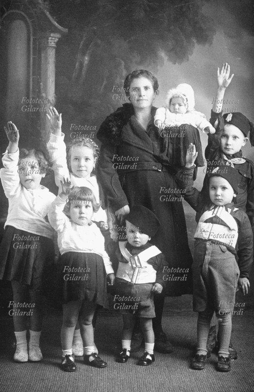 FASCISMO madre orgogliosa dei suoi sette figli, il minimo per ottenere il premio natalità. (saluto romano) Italia, 1935 circa.