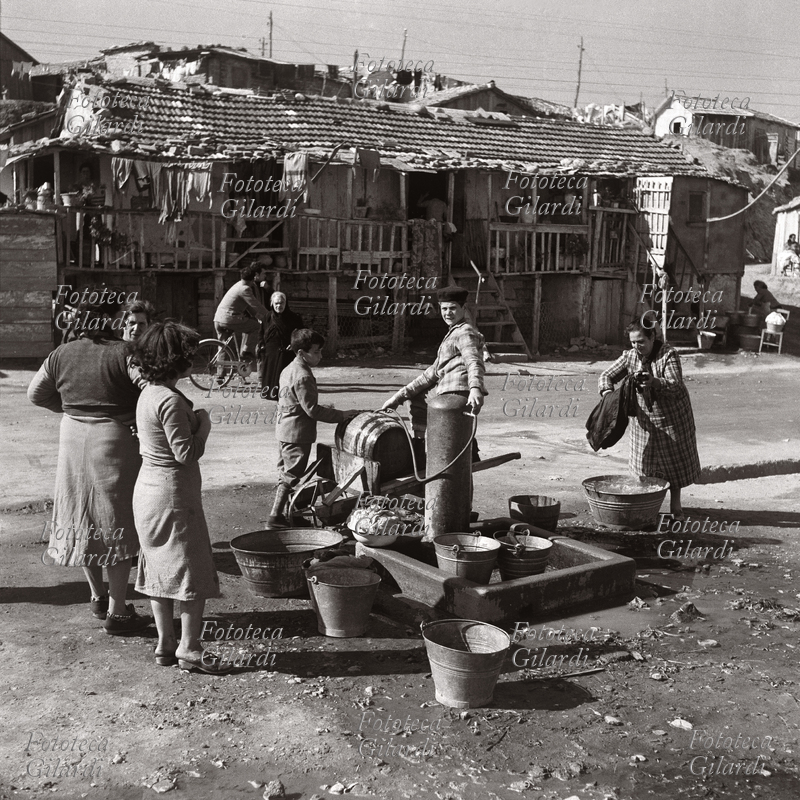 FAMIGLIA donne e ragazzini alla fontana si riforniscono d\