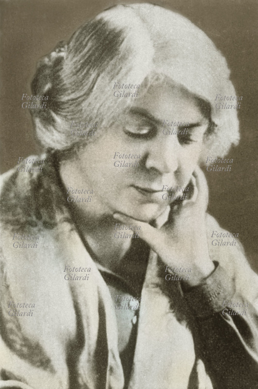 Grazia DELEDDA (27 settembre 1871 – 15 agosto 1936), scrittrice italiana nata a Nuoro, premio Nobel per la Letteratura nel 1926. Ritratto fotografico a mezzobusto, con il viso appoggiato ad una mano, leggermente colorato. Italia, 1920 circa.
